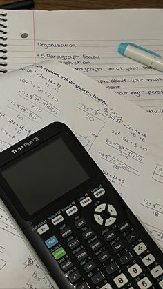 a calculator sitting on top of some paper with numbers and pencils next to it