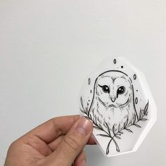 a hand holding an ornament with an owl on it's face and leaves