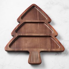 three wooden serving trays shaped like christmas trees on a white marble countertop, with one holding a fork and knife