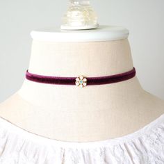 This charming choker necklace is handmade with a soft double sided velvet ribbon in a warm eggplant purple/burgundy hue. It features a sparkling Swarovski crystal flower jewel with opal pink and turquoise blue stones. See last group photos for a more of these pretty chokers, available separately in the Rosy Posy Designs shop. Treat yourself and get one for a friend! * Adjustable Length ~ 12 inches + 3 inch extender chain (fits a 12-15 inch circumference neck size)  * Band ~ 1/4 inch wide velvet band * Fastens with lobster clasp * Ships in a pretty gift box Discover more of Rosy Posy Designs unique handmade jewelry and gifts here: https://www.etsy.com/shop/rosyposydesigns?ref=si_shop Rosy Posy designs custom jewelry, pins and corsages for bride and bridesmaid dresses, sash flowers, hair acc Pretty Chokers, Rosy Posy, Flower Choker Necklace, Purple Burgundy, Flower Choker, Blue Stones, Eggplant Purple, Unique Handmade Jewelry, Crystal Flower