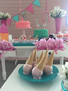 ice cream cones are sitting on a plate in front of cakes and desserts at a birthday party