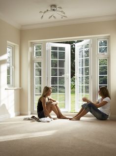 two women sitting on the floor in front of large windows