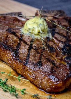 a steak is sitting on a cutting board with some green garnish around it