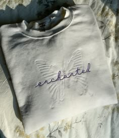 an embroidered t - shirt with the word enchanted on it sitting on a bed