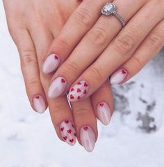 two hands holding each other with red and white hearts painted on their nails in the snow