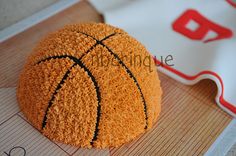 a cake made to look like a basketball on top of a mat with the letter b