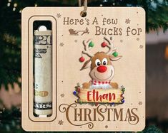 a christmas ornament hanging from a tree with money in the back and it's message here's a few bucks for elf