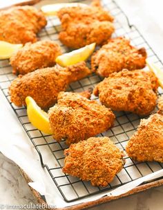 some fried food on a cooling rack with lemon wedges