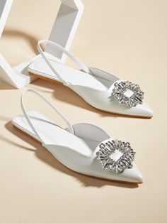 two white shoes with jeweled buckles on the front and back, sitting next to each other