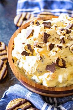 a wooden bowl filled with ice cream and chocolate chips on top of a table next to crackers