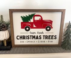 a red truck with a christmas tree on the back is sitting in front of some pine trees