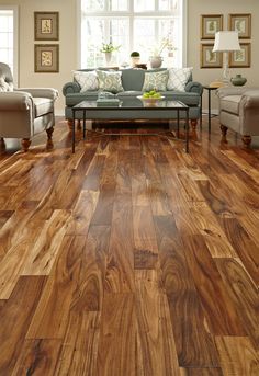 a living room with wood floors and furniture in the center, along with windows that look out onto the outside