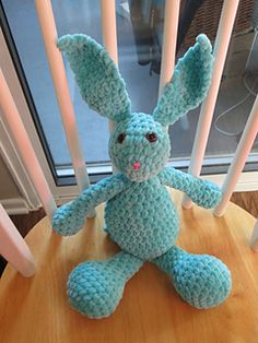 a crocheted blue bunny sitting on top of a wooden table