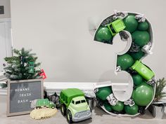 a green truck is parked in front of a large number 3 balloon decoration with christmas decorations around it