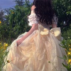 a woman in a yellow dress is sitting on the edge of a flowery field