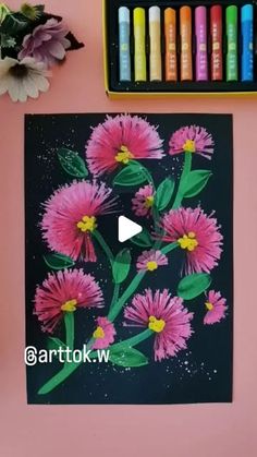 a pink flower with green leaves on it next to crayons