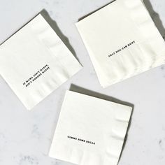 three white napkins with words on them sitting on a marble countertop next to each other