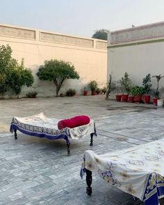 two beds covered with white and blue cloths sit in the middle of a courtyard