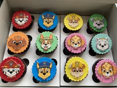 cupcakes decorated with cartoon dogs and fire fighters are in a box on the table