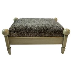 a leopard print footstool with wooden legs