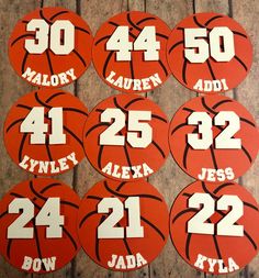 basketball name tags with numbers on them sitting on a wooden floor in front of a wall