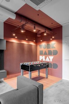 a room with a couch, foosball table and wall art on the walls