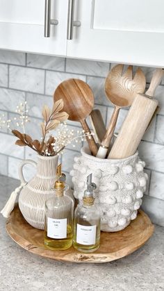 wooden utensils and spoons sit in a white vase on a wood tray