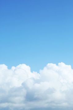 the airplane is flying high in the blue sky above the water and clouds below it