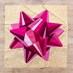 an origami star is on top of a piece of yellow and pink fabric