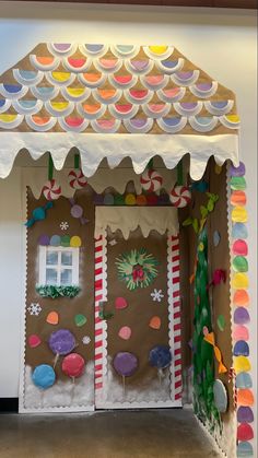 a gingerbread house made out of cardboard and paper plates with candy canes on the doors