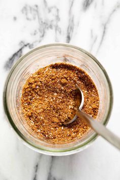 a jar filled with spices on top of a marble countertop next to a spoon