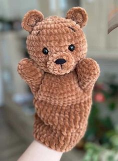 a brown teddy bear sitting on top of someones hand with it's thumb in the air