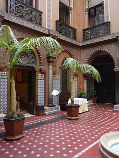 a courtyard with potted plants and tables in front of an ornately decorated building