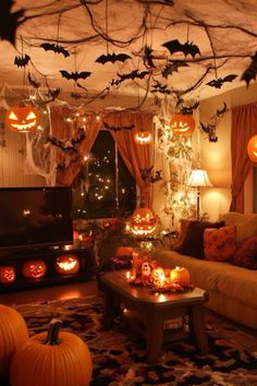 a living room decorated for halloween with pumpkins and bats hanging from the ceiling above