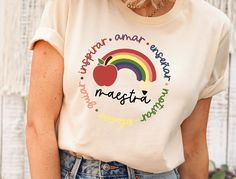 a woman wearing a white shirt with an apple on the front and rainbow in the back