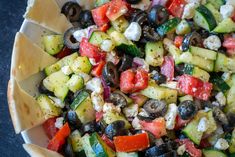 a salad with cucumbers, tomatoes, olives, and feta cheese