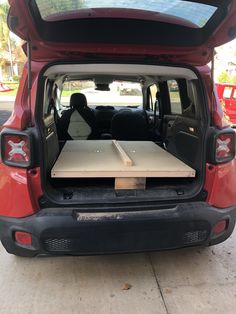 the back end of a red car with an open hatchback door and table in the trunk