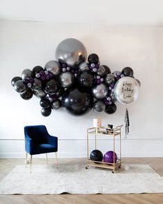 a balloon filled with black, silver and white balloons on top of a wooden floor