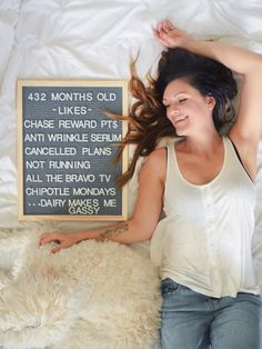 a woman laying on top of a white bed next to a sign that says 42 months old