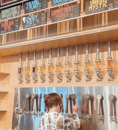 a woman standing in front of a display of beer taps