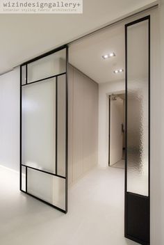 an empty room with white walls and black glass partitions on the wall, in front of a doorway