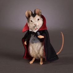 a mouse dressed in a cape and holding a mouse on its hind legs while standing up