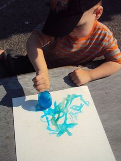 a young boy sitting at a picnic table painting