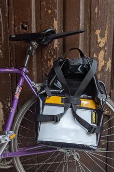 a purple bike with a white bag on the front rack and handlebars attached to it