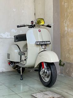 a white scooter parked next to a wall