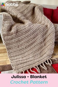 a crocheted blanket sitting on top of a wooden floor next to a couch