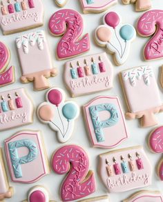 decorated birthday cookies on a white surface with pink and blue frosting, including one for the number two