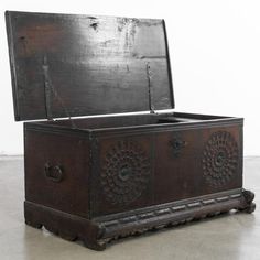 an old wooden trunk sitting on top of a cement floor next to a white wall