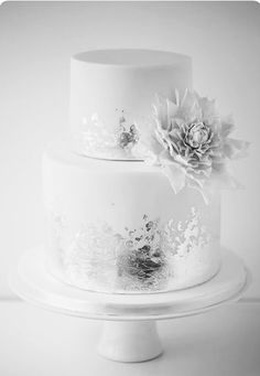 a three tiered white wedding cake with flowers on the top and bottom, in black and white