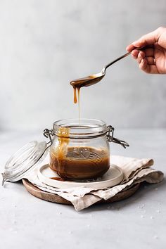 a person is spooning honey into a glass jar